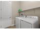 Bright laundry room with modern washer and dryer, utility shelf, and a door for easy access at 10972 Nicholas Jay Ave, Las Vegas, NV 89166