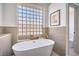 Luxurious bathroom features a freestanding tub, tile accent wall, and glass block window at 1144 Calico Ridge Dr, Henderson, NV 89011