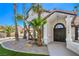 Home exterior with double-door entry, mature palm trees, and manicured gravel landscaping at 1144 Calico Ridge Dr, Henderson, NV 89011