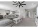 Open-concept living room with plush gray sofa, neutral decor, ceiling fan and access to the kitchen at 12413 Alpenglow Ct, Las Vegas, NV 89138