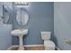 Powder room featuring a pedestal sink, oval mirror, and modern toilet at 1532 Via Cassia, Henderson, NV 89052