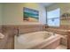 Bright bathroom featuring a soaking tub with tile surround, a window and a view of the backyard at 1532 Via Cassia, Henderson, NV 89052