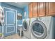Functional laundry room with a blue door, cabinets, washer, and dryer at 1532 Via Cassia, Henderson, NV 89052
