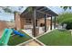 Landscaped backyard featuring a covered patio, a slide, and green lawn at 2598 Fountain Ave, Pahrump, NV 89048