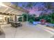 Expansive backyard with covered patio, dining area, custom pool, rock waterfall, and lush landscaping at 2940 Cimini Ct, Henderson, NV 89052