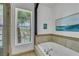 Cozy bathroom featuring a bathtub, neutral tile, and a window with natural light at 30 Via Vasari # 102, Henderson, NV 89011