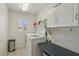 Efficient laundry room includes cabinets, folding table, window, and modern washer and dryer at 3194 Lapis Beach Dr, Las Vegas, NV 89117