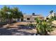 View of the spacious backyard featuring desert landscaping, a mature tree, and a patio area at 4285 El Como Way, Las Vegas, NV 89121