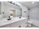Modern bathroom features dual sinks, granite countertop, black hardware, and tub with shower at 5217 Caspian Springs Dr # 101, Las Vegas, NV 89120