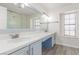 Bright bathroom featuring a long white countertop with double sinks, a large mirror, and blue cabinets at 5221 Crooked River Cir, Las Vegas, NV 89149
