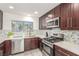 Modern kitchen featuring stainless steel appliances, wood cabinetry, mosaic tile backsplash, and stone countertops at 5221 Crooked River Cir, Las Vegas, NV 89149