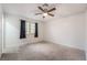 This bedroom has neutral carpet, a ceiling fan, and a window dressed with black curtains at 6711 W Charleston Blvd # 2, Las Vegas, NV 89146