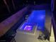Aerial view of a backyard pool and spa illuminated with colorful lights at night at 7020 Puetollano Dr, North Las Vegas, NV 89084