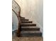 Carpeted staircase with a dark wood handrail and black iron spindles, complemented by neutral-toned walls and tile flooring at 7020 Puetollano Dr, North Las Vegas, NV 89084