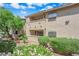 A two-story condo building with desert landscaping featuring green bushes and flowering pink plants at 7200 Pirates Cove Rd # 1011, Las Vegas, NV 89145