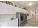Bright laundry room with modern washer and dryer units, white cabinetry, and countertops at 8356 Shady Lady Ct, Las Vegas, NV 89131