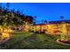 Backyard view showcases mature landscaping, outdoor seating, and a covered patio. It is well-lit for evening enjoyment at 853 Morning Sun Ct, Las Vegas, NV 89110