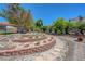 Picturesque backyard featuring a terraced garden with gravel paths, bordered by red brick and lush desert foliage at 853 Morning Sun Ct, Las Vegas, NV 89110