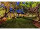 Lush backyard with a well-maintained lawn, patio, mature trees, and landscape lighting offers a relaxing retreat at 853 Morning Sun Ct, Las Vegas, NV 89110