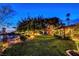 Serene backyard at twilight with mature trees, ambient lighting, and a distant city view at 853 Morning Sun Ct, Las Vegas, NV 89110