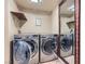 Convenient laundry room with side-by-side washer and dryer, shelf storage, and a full length mirror at 10159 Tumbling Tree St, Las Vegas, NV 89183