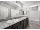 Double sink bathroom with granite countertop, dark wood cabinets, and walk-in shower at 2332 Mundare Dr, Henderson, NV 89002