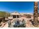 Relaxing backyard patio with a dining table and chairs surrounded by desert landscaping and mature trees at 2587 Grizzly Park Ct, Henderson, NV 89052