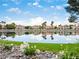 Beautiful waterfront view with reflections of homes and palm trees, enhanced by white flowers in the foreground at 2736 Huber Heights Dr, Las Vegas, NV 89128