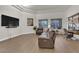 Open living room with a large tv, leather sectional, wood floors, and bright windows at 439 Pelican Bay Ct, Henderson, NV 89012