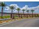 Community entrance featuring stone columns, palm trees, landscaping, and mountain views at 5662 Oak Bend Dr, Las Vegas, NV 89135