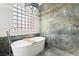 This modern bathroom has a soaking tub, marble tile, and large window with natural light at 5684 Benevento Ct, Las Vegas, NV 89141