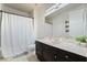 Clean, well-lit bathroom with a spacious vanity, neutral tiles and a shower with white patterned curtain at 5684 Benevento Ct, Las Vegas, NV 89141