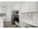 Well-appointed kitchen with white cabinetry, stainless steel appliances, a built-in desk, and stylish backsplash at 5684 Benevento Ct, Las Vegas, NV 89141