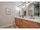 Bright bathroom featuring a double sink vanity with wood cabinets, quartz countertops, and modern fixtures at 5757 Charles Holden Ct, Las Vegas, NV 89103