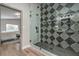 Stunning shower with glass door and geometric tile design, complemented by modern fixtures and gray tile flooring at 5757 Charles Holden Ct, Las Vegas, NV 89103