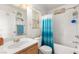 Bright bathroom with vanity, mirror, and a tub/shower combination with blue shower curtain at 6488 Bentley Wood Ct, Las Vegas, NV 89130