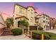 The exterior of a tan two-story townhome featuring an attached garage and small front yard at 6488 Bentley Wood Ct, Las Vegas, NV 89130