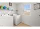A bright laundry room with washer, dryer, overhead shelving, and a window at 6488 Bentley Wood Ct, Las Vegas, NV 89130