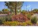 Landscaped community entrance with a decorative rock sign, flowers, and lush greenery, enhancing neighborhood charm at 6649 Maple Mesa St, North Las Vegas, NV 89084