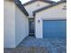 Home's front entrance and attached two car garage with a blue door at 73 Hawk Ave, Pahrump, NV 89060