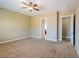 Expansive bedroom with neutral tones, plush carpet, a ceiling fan, and doorways for easy access at 7434 Eggshell Dr, North Las Vegas, NV 89084
