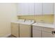Well-lit laundry room with washer, dryer, sink, and ample storage space at 7434 Eggshell Dr, North Las Vegas, NV 89084
