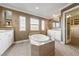 Elegant bathroom featuring a standalone tub with decorative windows, white cabinetry, and mosaic tile flooring at 7438 Desertscape Ave, Las Vegas, NV 89178