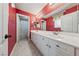 Bright bathroom with double vanity, red patterned wallpaper, and access to a separate toilet and shower area at 7438 Desertscape Ave, Las Vegas, NV 89178