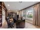 Inviting home office with built-in shelving, black desk and large windows overlooking landscaped yard at 7438 Desertscape Ave, Las Vegas, NV 89178