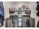 Efficient laundry room featuring modern stainless steel washer and dryer, and practical overhead storage shelves at 76 Summer Rhapsody Ave, Henderson, NV 89015