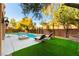 Lounge by the pool in this backyard oasis, featuring lush green lawns and privacy landscaping at 10002 Trapper Mountain St, Las Vegas, NV 89178