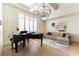 Elegant living room features a piano, modern chandelier, and large windows at 10002 Trapper Mountain St, Las Vegas, NV 89178