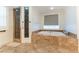 Luxurious main bathroom features a soaking tub, a glass-enclosed shower, and warm earthy tones throughout at 10002 Trapper Mountain St, Las Vegas, NV 89178