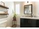 Stylish powder room featuring a black vanity, white countertop and modern fixtures, accented with floating shelves and decor at 10002 Trapper Mountain St, Las Vegas, NV 89178